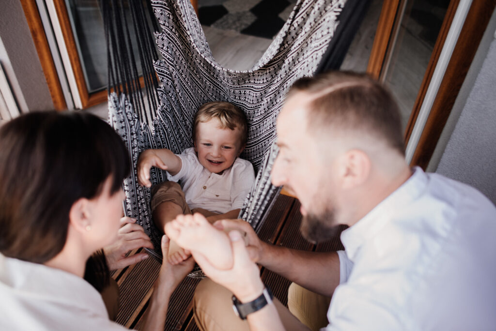 rodzice huśtają dziecko w hamaku na sesji rodzinnej  